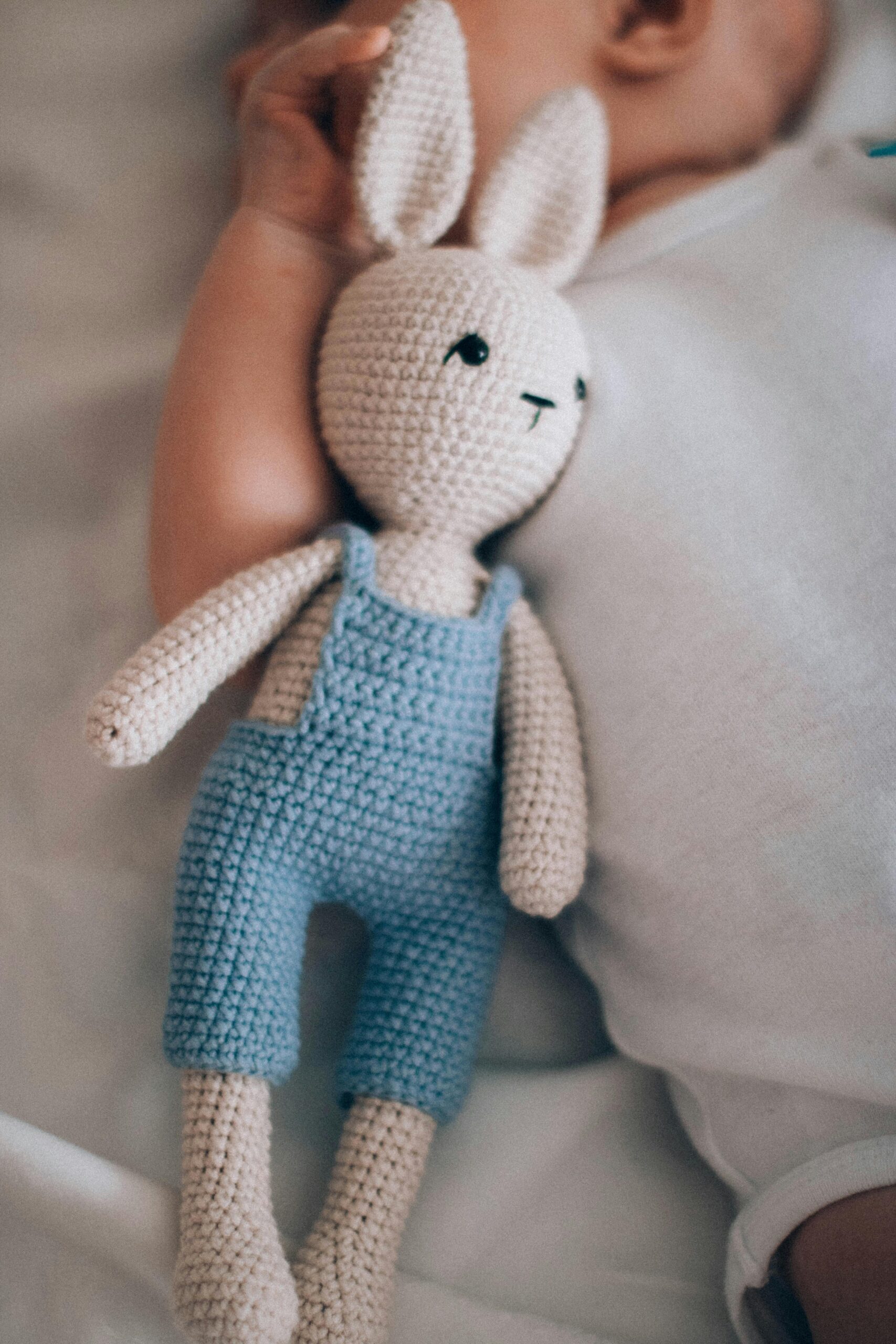 pexels photo 2731820 2731820 A cute baby lies next to a handmade crochet bunny doll in soft lighting.